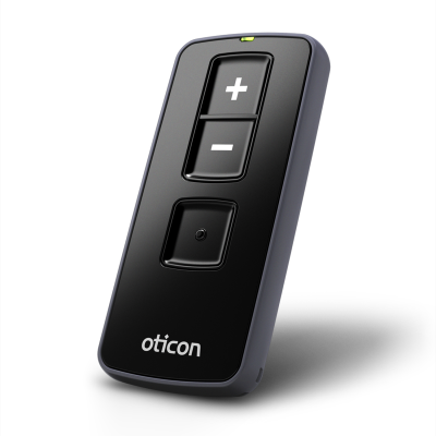 The Oticon Remote Control 3.0 is a sleek black device with three buttons: a large plus (+) at the top, a minus (–) in the center, and a round button below, finished with Oticon branding at the base.