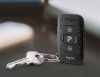 A pair of silver keys is attached to a black Signia miniPocket device with multiple buttons, including a P button, shown on a smooth dark surface.