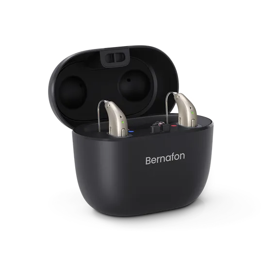 A pair of beige hearing aids sit in an open Bernafon Charger Plus miniRITE case with the Bernafon logo on the front, all set against a plain white background.